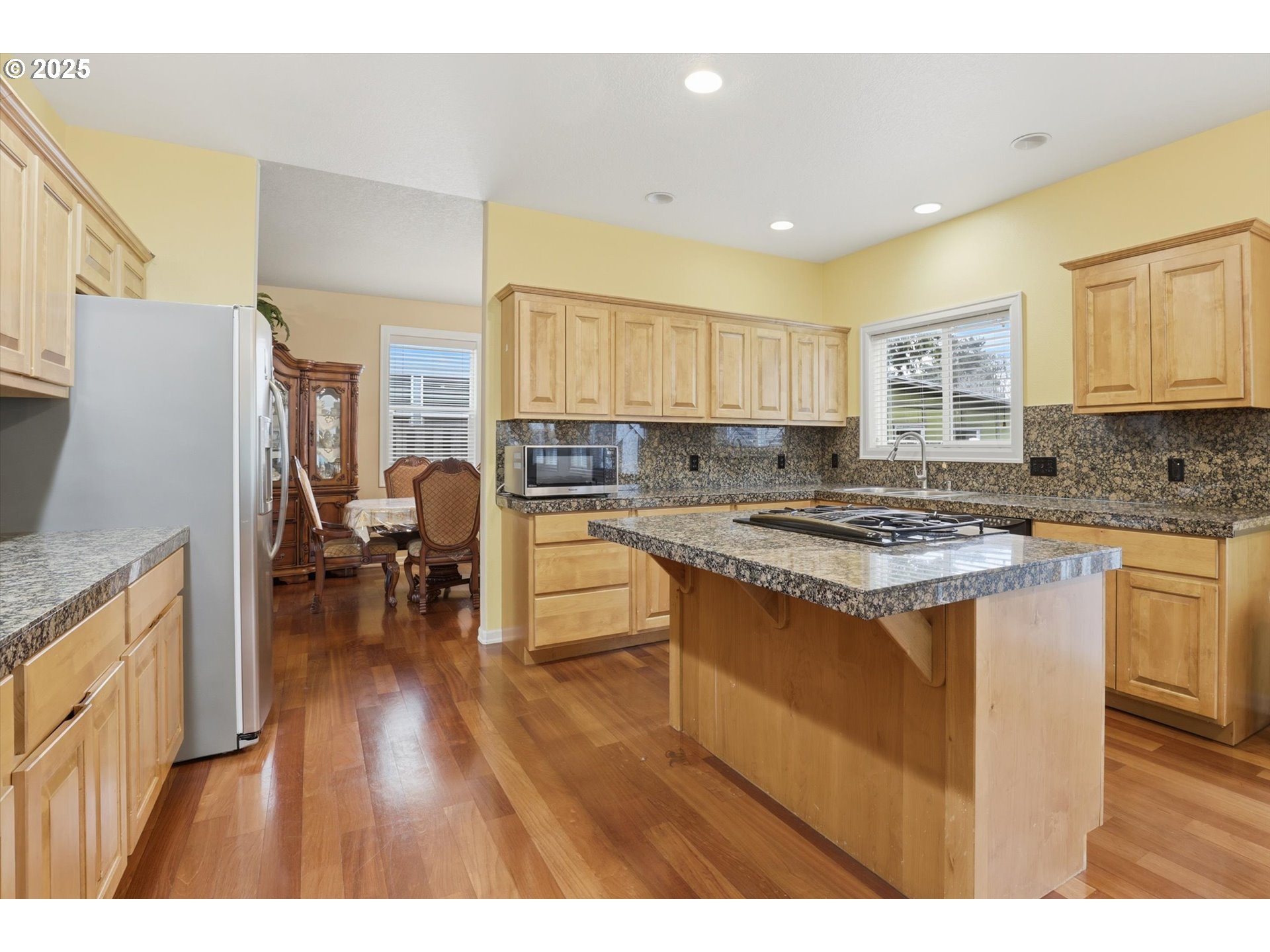 3718 Southeast 127th Place Portland, OR 97236 - Photo 11 of 31 a kitchen with stainless steel appliances granite countertop a stove top oven a sink dishwasher a dining table and chairs with wooden floor