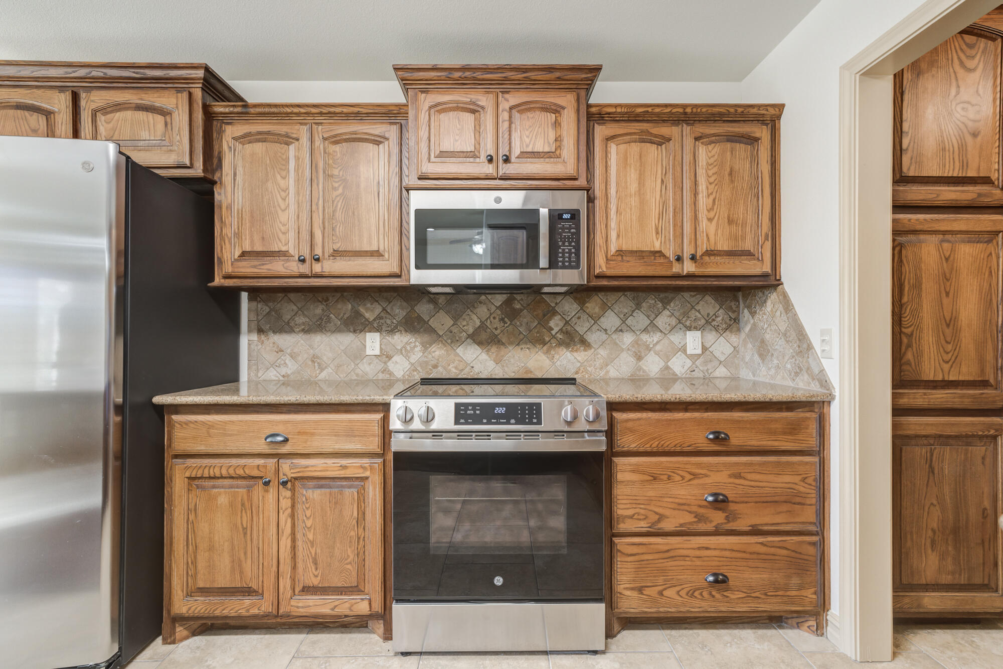 6509 72nd Street Lubbock, TX 79424 - Photo 12 of 40 a kitchen with granite countertop a stove and a microwave