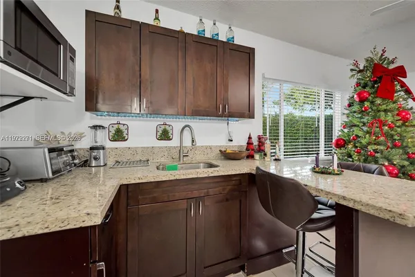 a kitchen with a sink a microwave a dining table and chairs