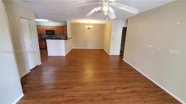 a view of a hallway with wooden floor and a kitchen space