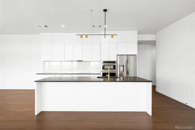 a view of kitchen with stainless steel appliances wooden floor and window