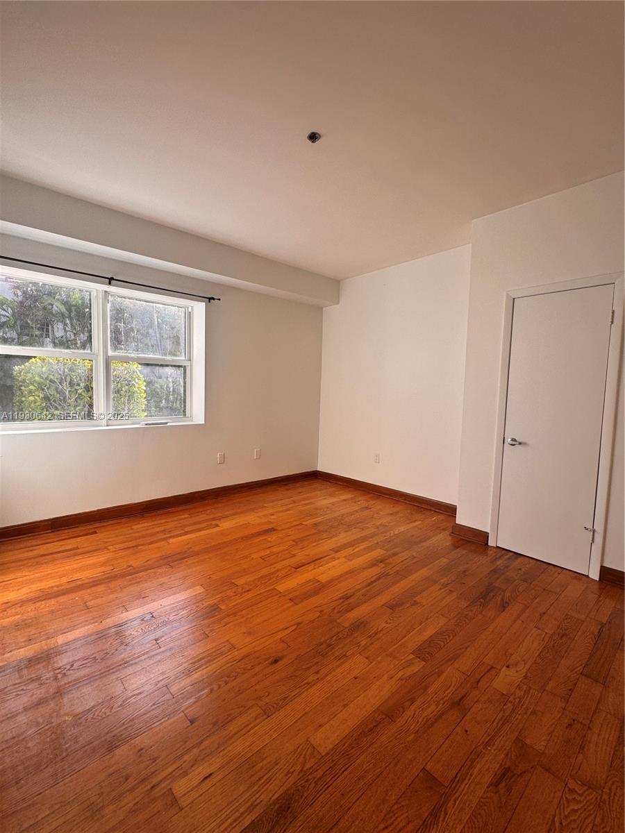 361 Collins Avenue, Unit A2 Miami Beach, FL 33139 - Photo 23 of 25 a view of an empty room with wooden floor and a window
