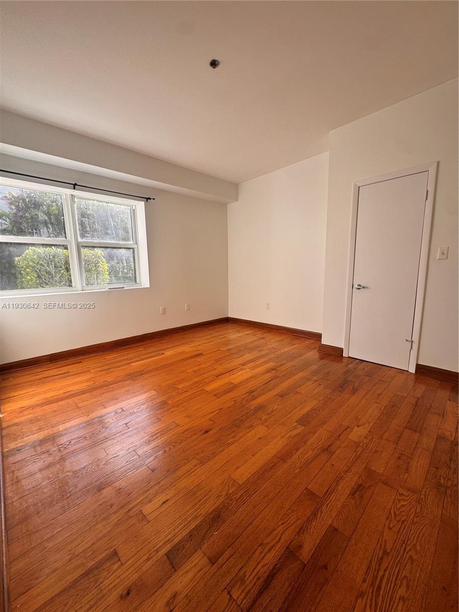 361 Collins Avenue, Unit A2 Miami Beach, FL 33139 - Photo 24 of 25 an empty room with wooden floor and windows
