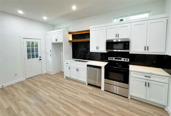 a kitchen with stainless steel appliances a white stove top oven and white cabinets