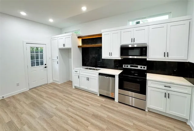 a kitchen with stainless steel appliances a white stove top oven and white cabinets