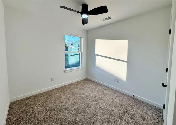 an empty room with windows and fan
