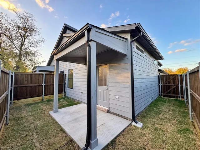a view of wooden house with a small yard and wooden fence