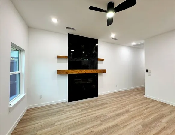 a view of an empty room with kitchen and a window