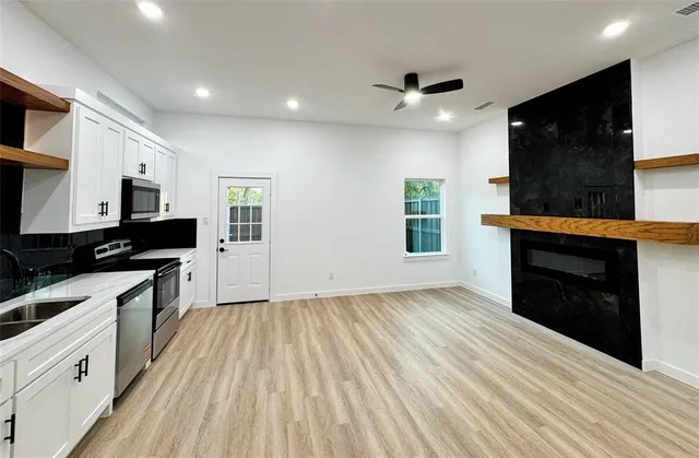 a kitchen with granite countertop a stove top oven a sink dishwasher and a refrigerator with wooden floor