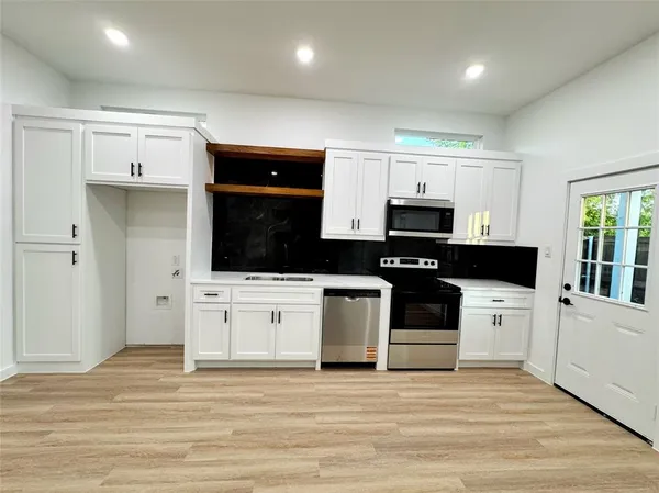 a kitchen with granite countertop a stove a sink and a microwave