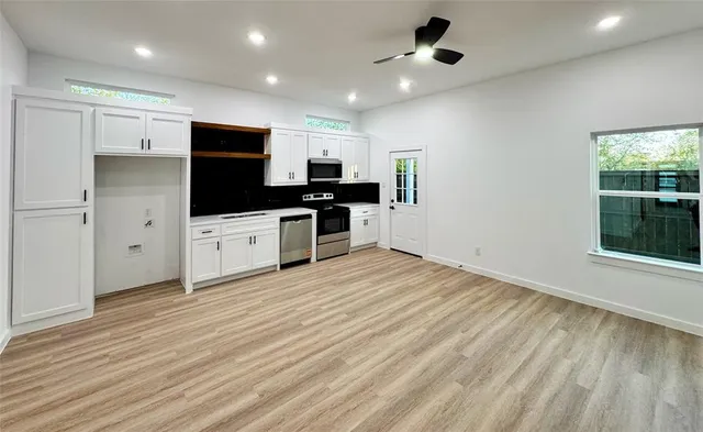 a kitchen with stainless steel appliances a stove top oven a sink a refrigerator with wooden floors and cabinets