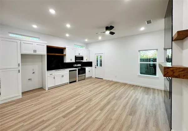 a large kitchen with stainless steel appliances kitchen island a large counter top a stove and a wooden floors
