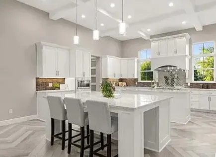 a kitchen with kitchen island granite countertop a sink and white cabinets