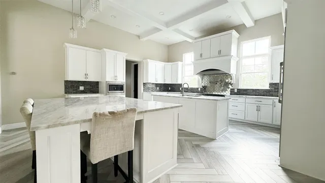 a large white kitchen with cabinets a sink and appliances