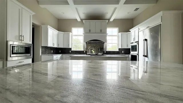 a large kitchen with stainless steel appliances kitchen island granite countertop a sink and cabinets