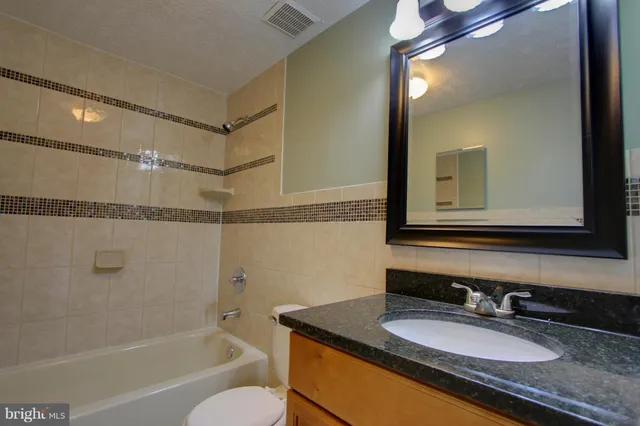 a bathroom with a granite countertop sink mirror and a bathtub