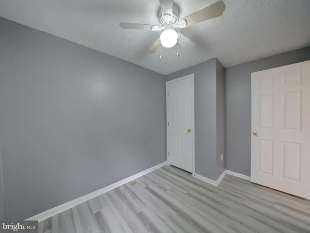 an empty room with wooden floor and ceiling fan