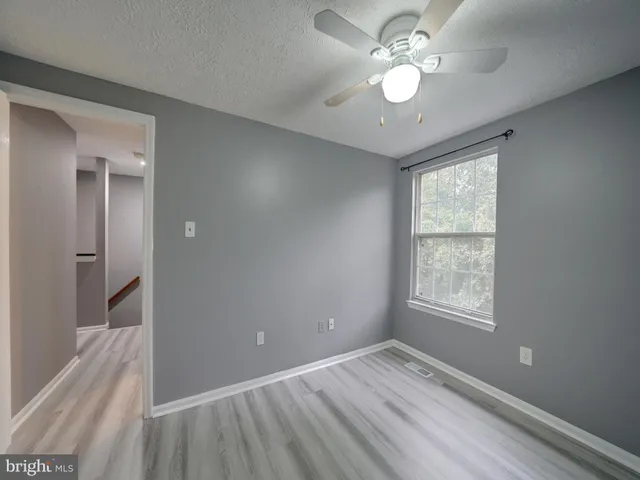 a view of an empty room and window and chandelier fan