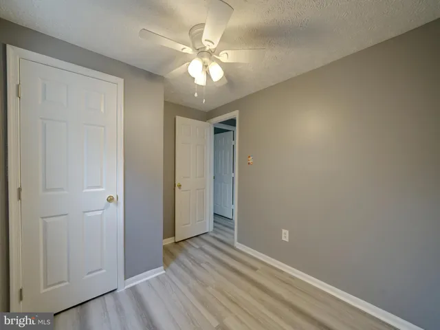 an empty room with wooden floor and chandelier fan