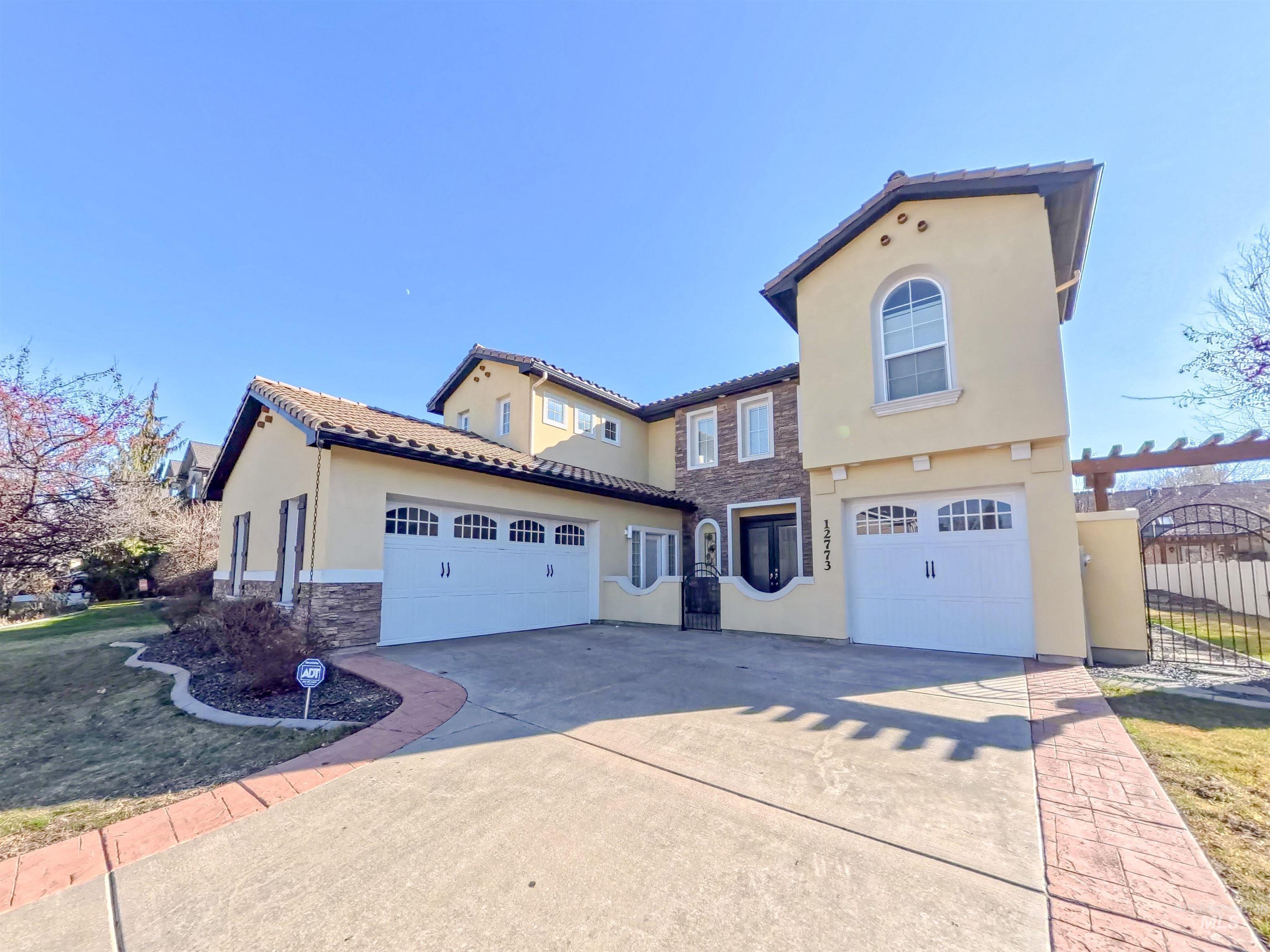Mediterranean / spanish home featuring stone siding, stucco siding, driveway, and a gate