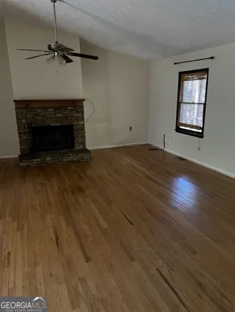 an empty room with wooden floor a fireplace and windows