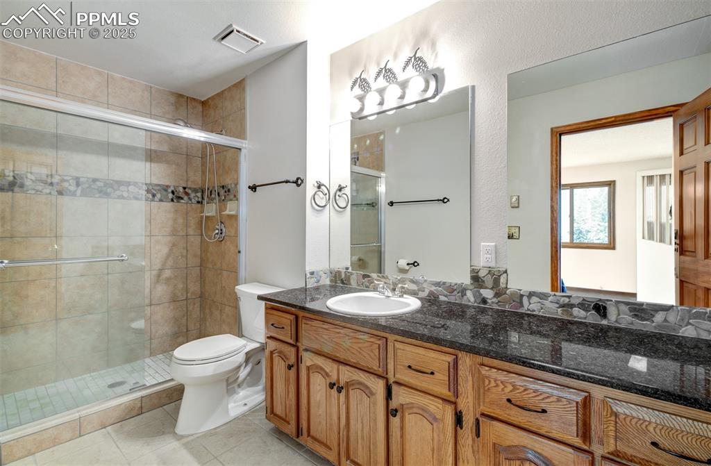 5865 Waterfall Loop Manitou Springs, CO 80829 - Photo 18 of 45 a bathroom with a granite countertop sink toilet a mirror and shower