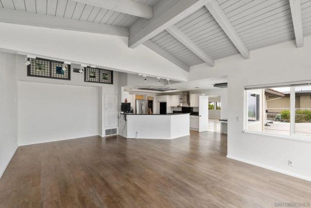 a view of a big room with wooden floor and windows