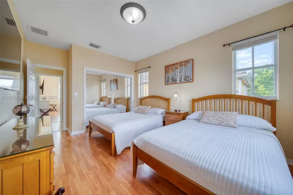 a bedroom with two beds and a dresser next to a window