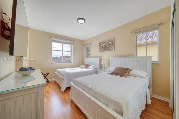a bedroom with two beds and a dresser next to a window