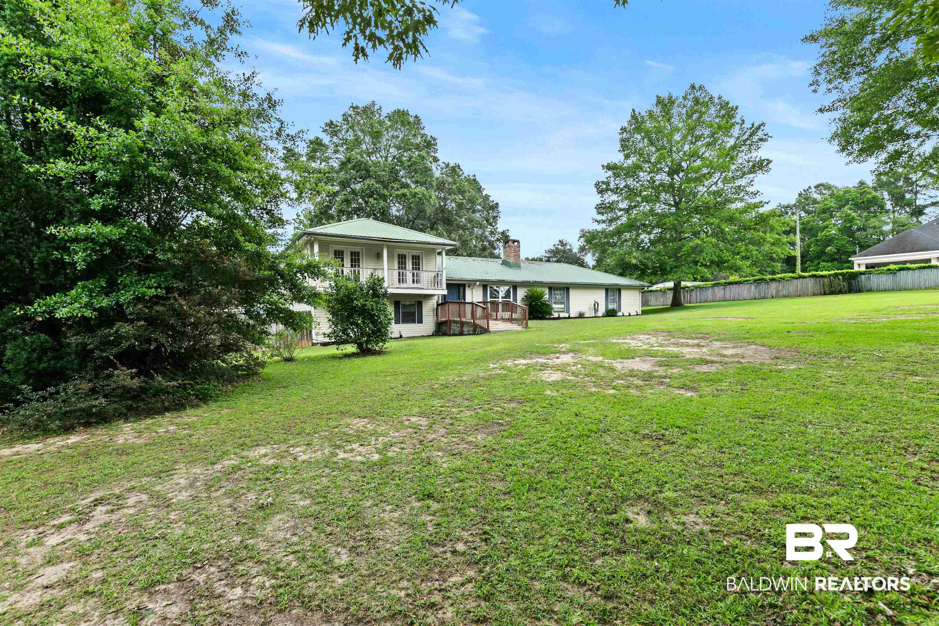 10420 Johnson Road South Mobile, AL 36695 - Photo 9 of 75 Expansive rear lawn framed by mature trees, featuring a light-colored exterior with a green roof
