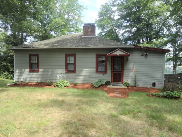 a front view of house with yard and trees in the background