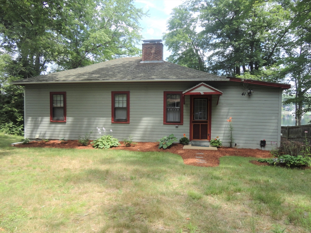 a front view of house with yard and trees in the background