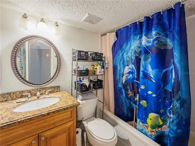 a bathroom with a granite countertop toilet sink and mirror