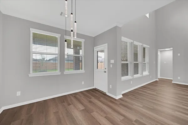 a view of an empty room with wooden floor fireplace and a window