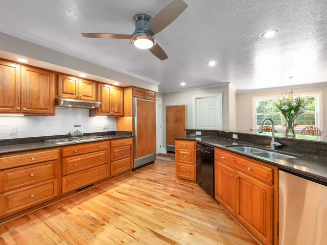 a large kitchen with kitchen island granite countertop a sink stainless steel appliances and cabinets