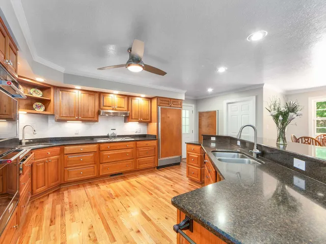a large kitchen with granite countertop a large counter top a sink stainless steel appliances and cabinets