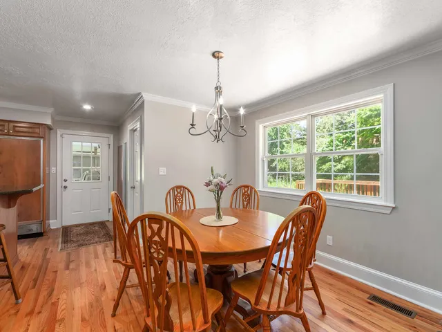 a dining room with furniture a chandelier and wooden floor