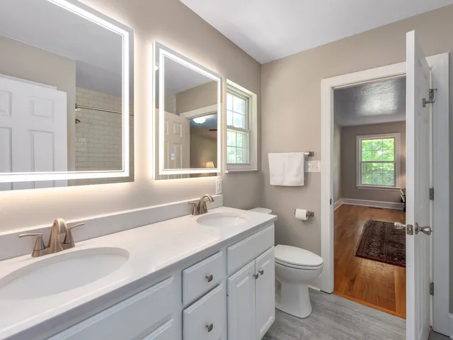 a bathroom with a granite countertop toilet sink and mirror