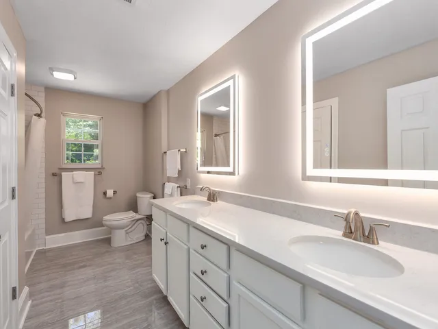 a bathroom with a granite countertop double vanity sink a mirror and a toilet