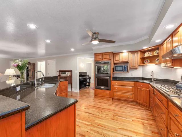 a kitchen with stainless steel appliances granite countertop a sink counter space and wooden floors