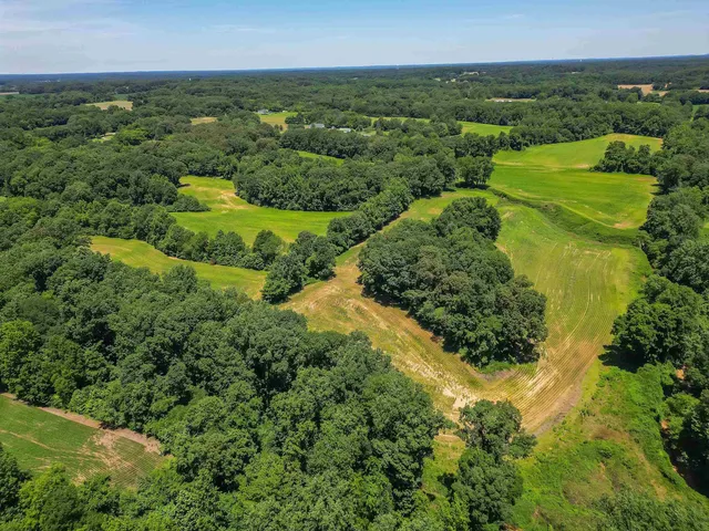 an aerial view of residential houses with outdoor space and trees all around
