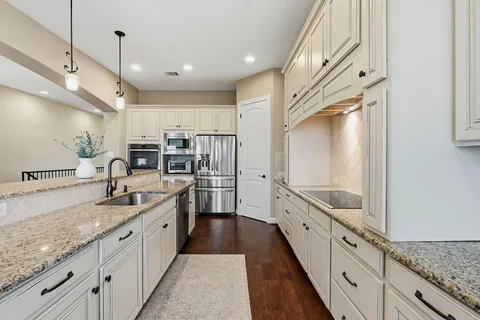 a kitchen with granite countertop a sink and white cabinets
