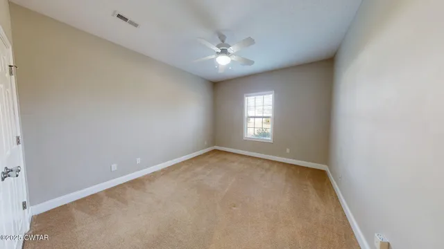 an empty room with a ceiling fan and window