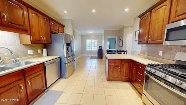 a kitchen with stainless steel appliances granite countertop wooden cabinets a stove top oven a sink and dishwasher