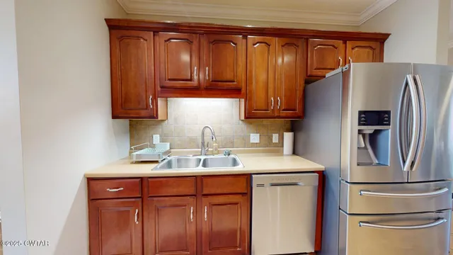 a kitchen with stainless steel appliances granite countertop a refrigerator a sink and wooden cabinets