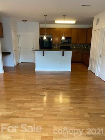 630 Calvert Street, Unit 409 Charlotte, NC 28208 - Photo 2 of 11 a view of a kitchen with kitchen island a sink wooden floor and a counter top space