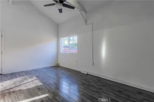 an empty room with wooden floor chandelier fan and windows