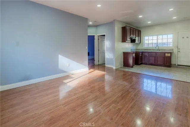 a view of an empty room with window and wooden floor