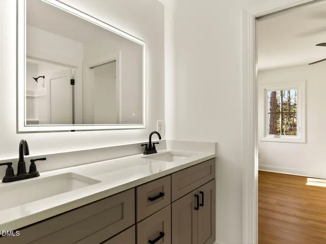 a bathroom with a toilet a sink a window and mirror