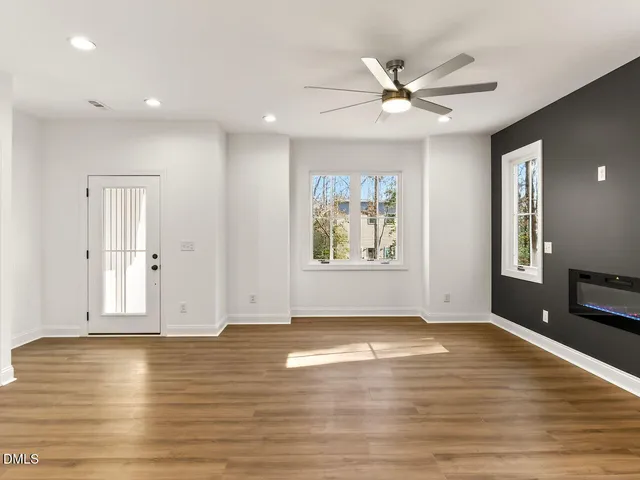 a view of an empty room with window and wooden floor